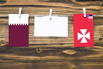 Hanging flags of Qatar and Wallis And Futuna attached to rope with clothes pins with copy space on...