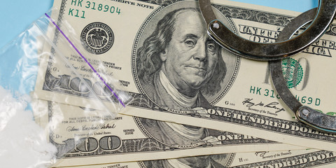 A bag of drugs, US dollars and handcuffs on the table.