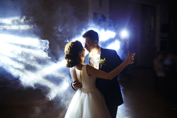 First wedding dance of newlywed. Wedding couple dancing in the darkness. Groom holds bride's hand...