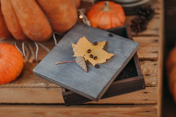 Autumn decor with wooden box, pumpkins, yellow leaves and pine's cone.