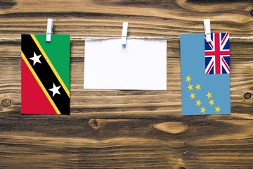 Hanging flags of Saint Kitts And Nevis and Tuvalu attached to rope with clothes pins with copy...