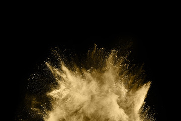 Golden powder explosion on black background. Freeze motion.