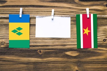 Hanging flags of Saint Vincent And The Grenadines and Suriname attached to rope with clothes pins...