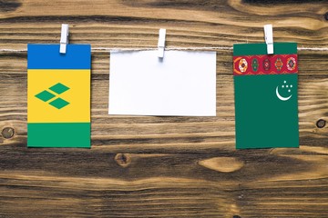 Hanging flags of Saint Vincent And The Grenadines and Turkmenistan attached to rope with clothes...