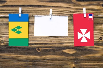 Hanging flags of Saint Vincent And The Grenadines and Wallis And Futuna attached to rope with...