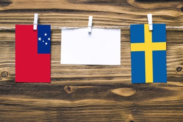 Hanging flags of Samoa and Sweden attached to rope with clothes pins with copy space on white note...