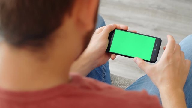 Sports Fan Reaction Concept - Excited sports fan watching his favourite team/player on smartphone with green screen at home, 4k slow motion