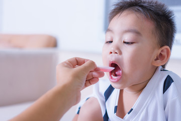 Asian children boy sick he take medicine by spoon