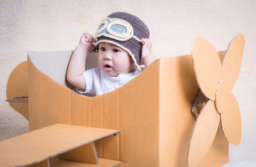 Baby child flies with plane of cardboard box