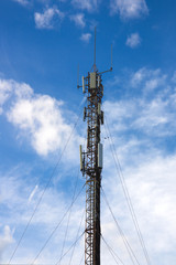 Obraz premium View of a mobile phone antenna from the ground with clouds and glades in the blue sky