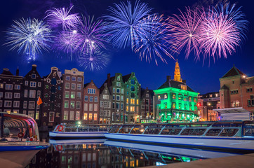 Traditional old buildings and boats with fireworks at night in Amsterdam, Netherlands.