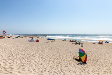 Fototapeta na wymiar View at the beach with people taking sunbath on beach. Atlantic Ocean, Costa Nova, Portugal