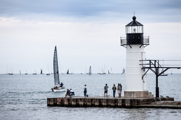 Fototapeta na wymiar Sailboats gather for the final leg of a regatta, focus on lighthouse