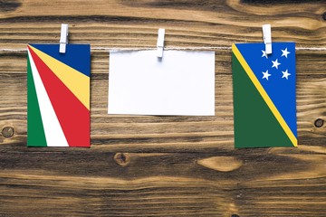 Hanging flags of Seychelles and Solomon Islands attached to rope with clothes pins with copy space...