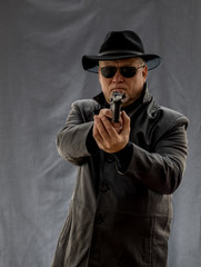 A man in black clothes, a black leather coat, hat. Ganster with a cigar Mauser system pistol. Mafiosi in black glasses on a dark background. Severe, strong, stylish, impressive, dangerous, unfriendly,