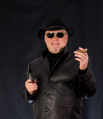 A man in black clothes, a black leather coat, hat. Ganster with a cigar Mauser system pistol. Mafiosi in black glasses on a dark background. Severe, strong, stylish, impressive, dangerous, unfriendly,