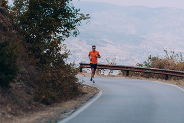 Muscular fit sport model sprinter exercising sprint on forest road