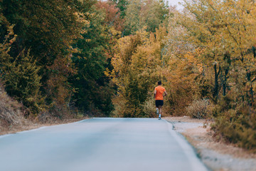 Runner athlete running on forest trail. Man fitness jogging workout wellness concept