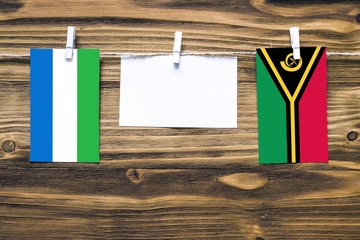 Hanging flags of Sierra Leone and Vanuatu attached to rope with clothes pins with copy space on...