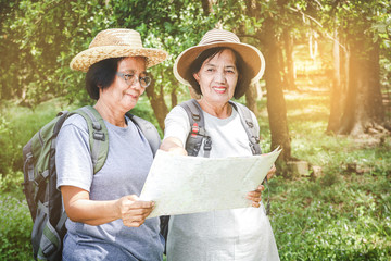 Two elderly women hiking Carrying a backpack and carrying a map. The concept of senior citizens traveling nature