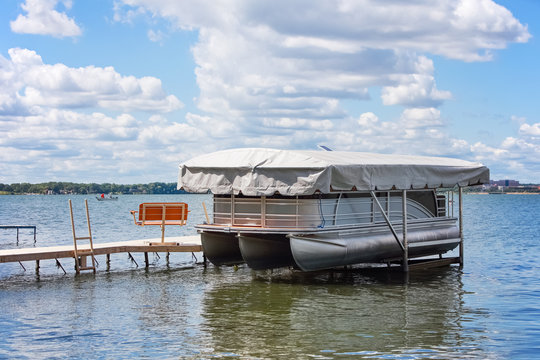 Pontoon boat with cover resting in boat lift on an inland lake