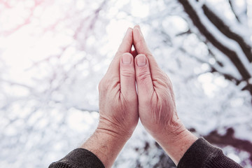 Praying hands lifted up to the sky in winter
