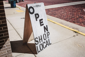 Open shop local sign on a wooden sandwich board outside of a store
