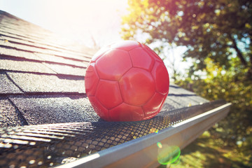 Soccer ball stuck on gutter mesh on a roof
