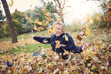 Boy taking a break from raking to play in a leaf pile