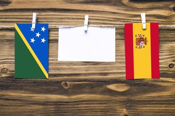 Hanging flags of Solomon Islands and Spain attached to rope with clothes pins with copy space on...