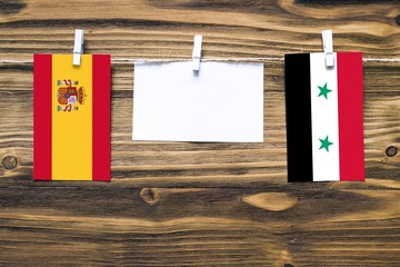 Hanging flags of Spain and Syria attached to rope with clothes pins with copy space on white note...