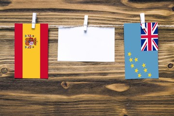 Hanging flags of Spain and Tuvalu attached to rope with clothes pins with copy space on white note...
