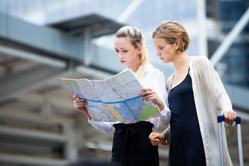 Travel and tourism concept. Two caucasian Woman traveler tourist walking with luggage and looking the map in the city