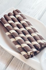 Delicious sweet snack. Tubes with chocolate and cream inside on a white plate.