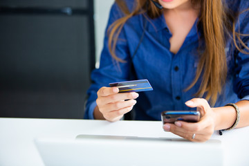 online shopping concepts. Woman hand  holding mobile phone and credit card with Payment Detail page display. using smartphone and laptop computer for online shopping