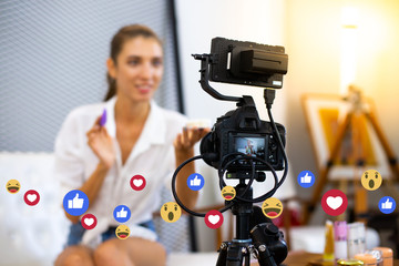 Young woman fashion blogger recording new content for vlog with camera on foreground at home