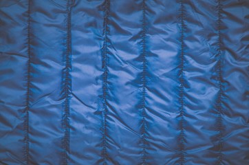 Shiny clothing background. Dark blue background from quilted material.