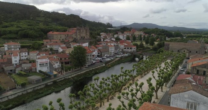 Aerial: Trees by Sar River amidst buildings in town of Padron against sky