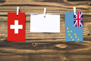 Hanging flags of Switzerland and Tuvalu attached to rope with clothes pins with copy space on white...