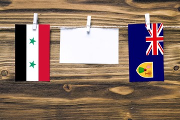 Hanging flags of Syria and Turks And Caicos Islands attached to rope with clothes pins with copy...