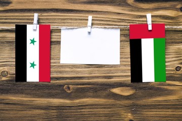 Hanging flags of Syria and United Arab Emirates attached to rope with clothes pins with copy space...