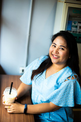 Cute overweight woman in coffee cafe, Happy Asian woman in a cafe with plastic cup coffee