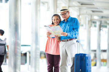 Travel and tourism concept. Happy Senior couple woman and man traveling together looking for destination with city map