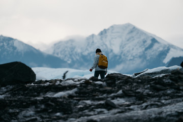 Young woman in denim jacket and backpack walking on glacier in Alaska