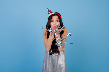 beautiful woman blowing silver confetti wearing hoop with christmas tree isolated over blue