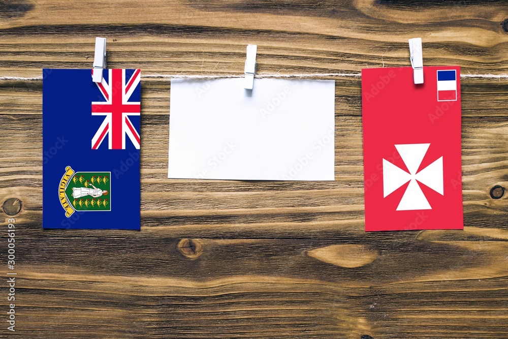 Wall mural Hanging flags of British Virgin Islands and Wallis And Futuna attached to rope with clothes pins with copy space on white note paper on wooden background.Diplomatic relations between countries.