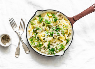 Fresh papardelle with chicken ragout  , green peas and fennel in pan on wooden rustic board on light background, top view