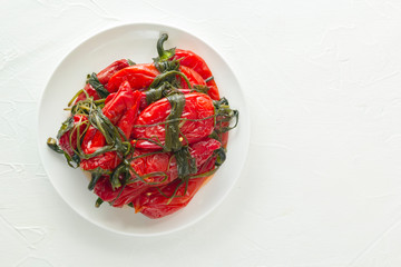 Traditional Korean fermented food - red hot peppers with herbs on a white table. Top view. Copy space