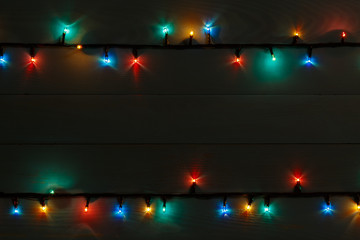 Christmas lights on a dark wooden background. Copy space. View from above.