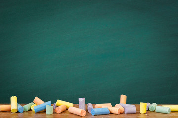 Group of colorful chalks and a blackboard or chalkboard background, concept for education, banner, startup, teaching , etc. © tonstock